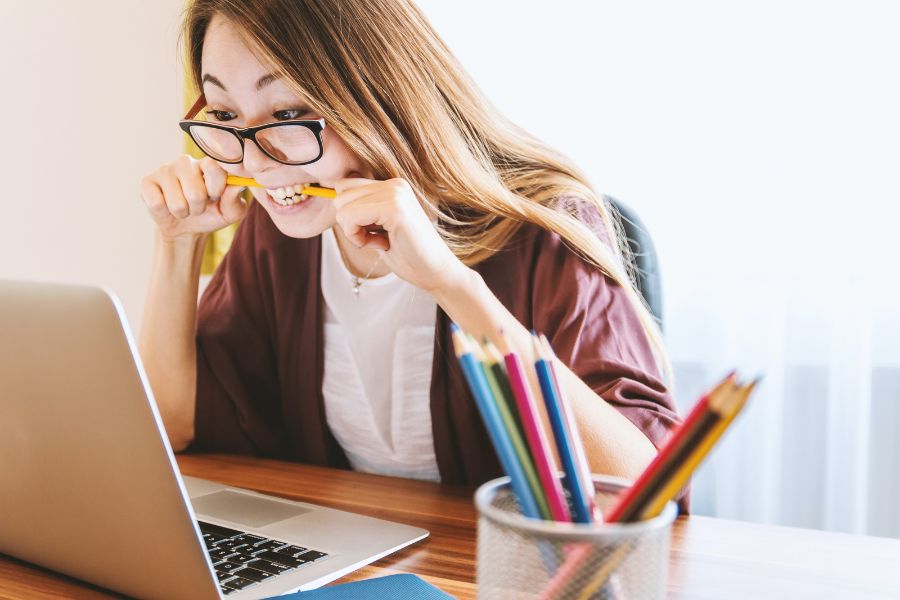 Ragazza che morda una matita mentre si accorge di alcuni errori fatti mentre scrive una newsletter