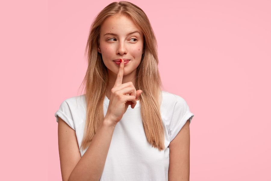 Ragazza che fa segno di stare in silenzio mettendo un indice sulla bocca