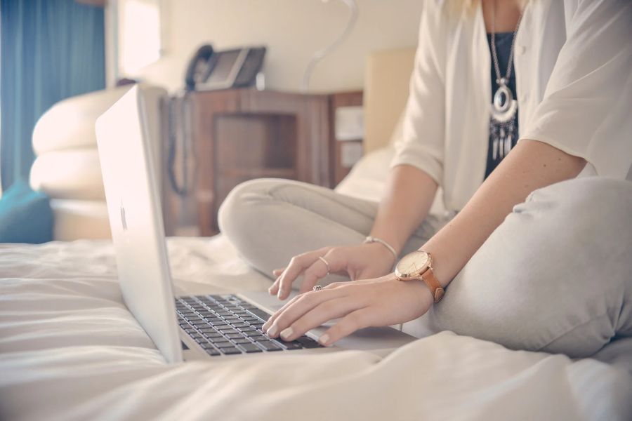 Ragazza seduta sul letto mentre lavora al computer