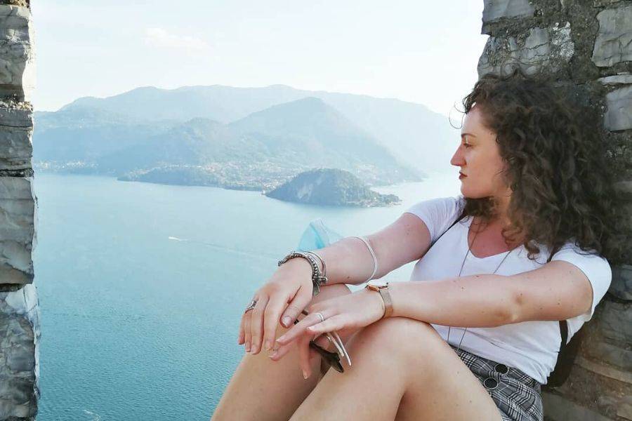 Maria Grazia De Falco seduta su un muretto che guarda il lago