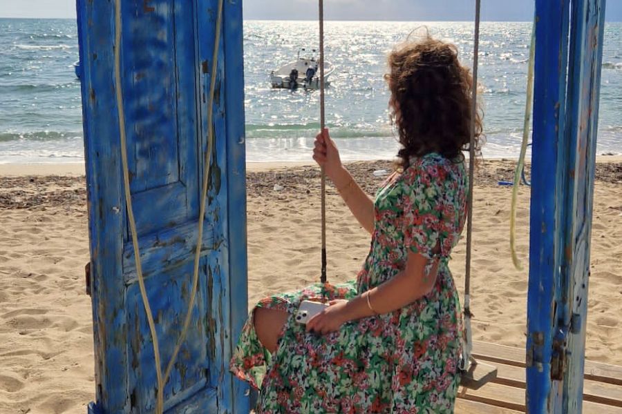 Ragazza che siede su un'altalena in riva al mare