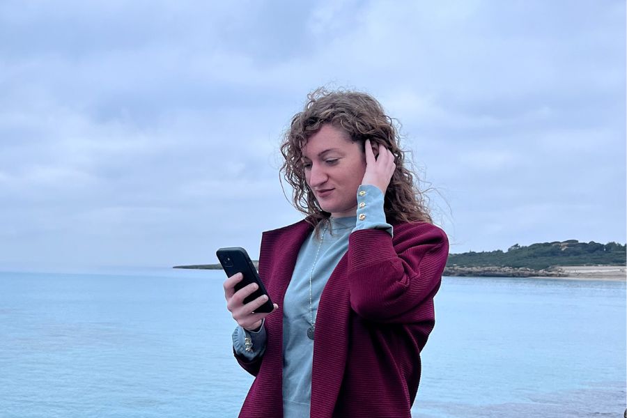 Ragazza che legge qualcosa sul cellulare. sullo sfondo il mare