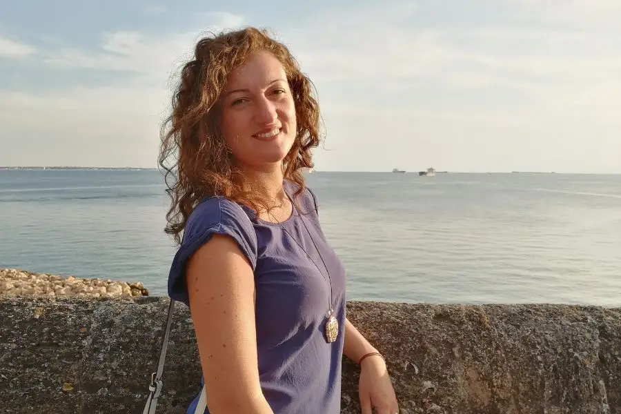 Ragazza appoggiata al muretto. Sullo sfondo si vede il mare