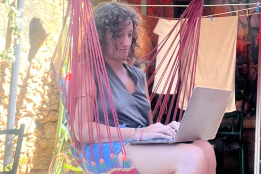 Ragazza che lavora al computer mentre &egrave; seduta su un'amaca